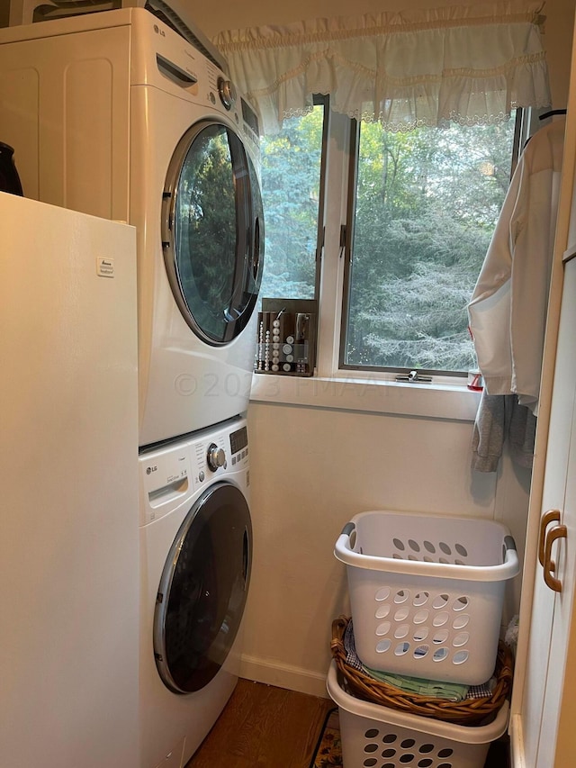 laundry area with stacked washer / drying machine and wood-type flooring