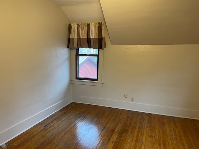 empty room with dark wood-type flooring and vaulted ceiling