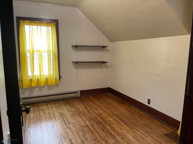 additional living space featuring lofted ceiling, hardwood / wood-style flooring, and baseboard heating