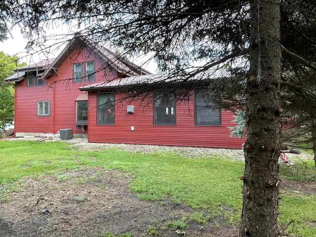 back of property featuring central air condition unit and a yard