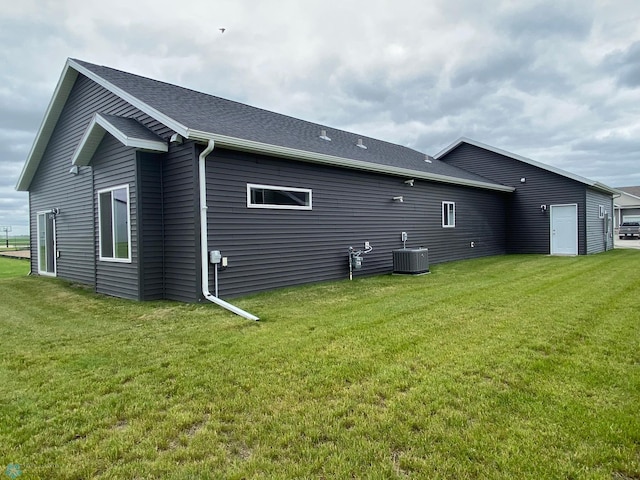 rear view of property featuring a lawn and central air condition unit