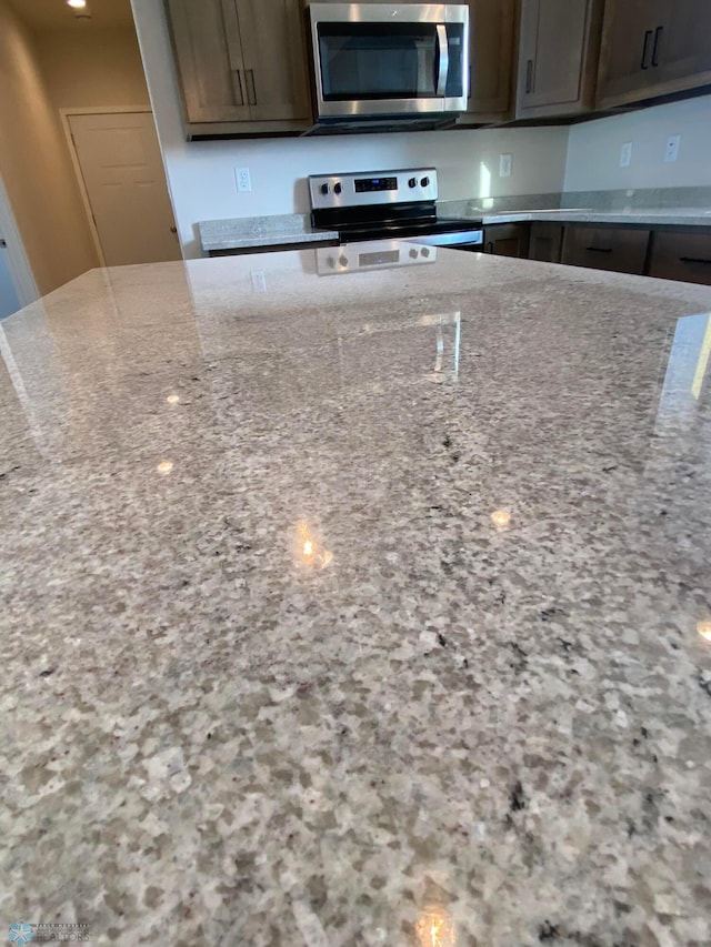 kitchen featuring light stone countertops, dark brown cabinets, and appliances with stainless steel finishes