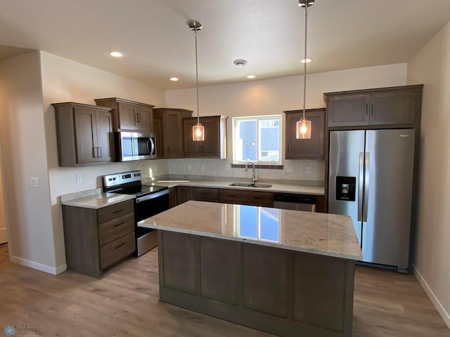 kitchen featuring decorative backsplash, appliances with stainless steel finishes, sink, pendant lighting, and a center island