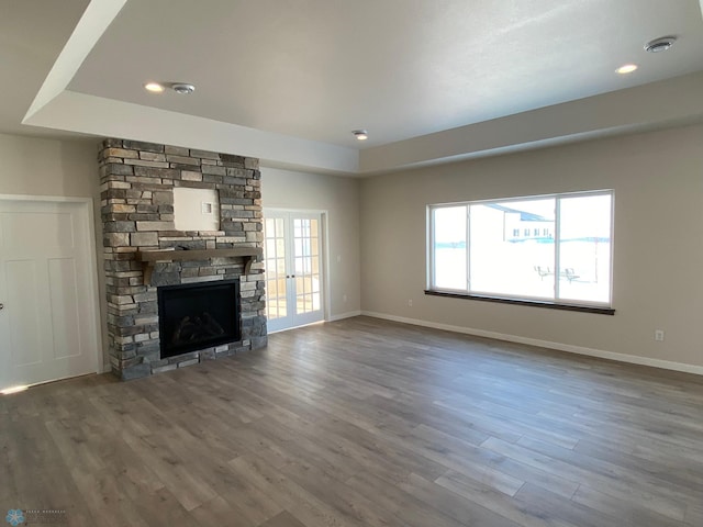 unfurnished living room featuring a raised ceiling, a fireplace, french doors, and hardwood / wood-style flooring