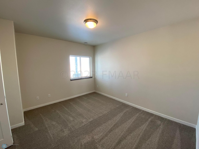 spare room featuring dark colored carpet