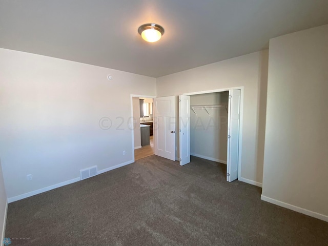 unfurnished bedroom with dark carpet and a closet