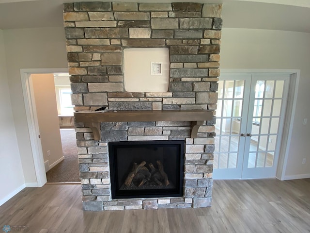 detailed view of french doors, a fireplace, baseboards, and wood finished floors