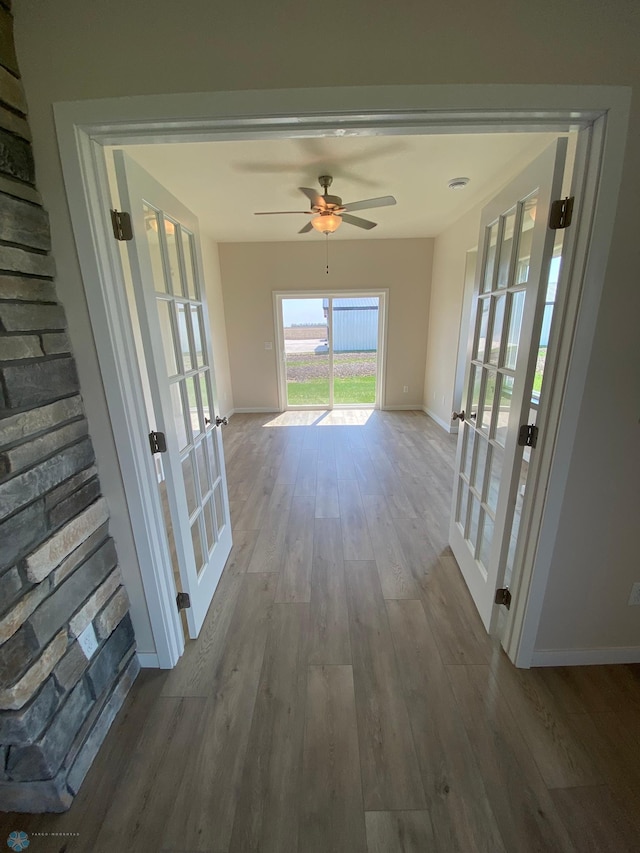 hall with french doors, wood finished floors, and baseboards