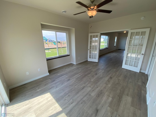 unfurnished room with french doors, a ceiling fan, wood finished floors, and baseboards
