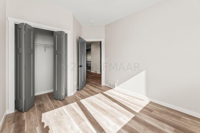 unfurnished bedroom with light hardwood / wood-style flooring and a closet