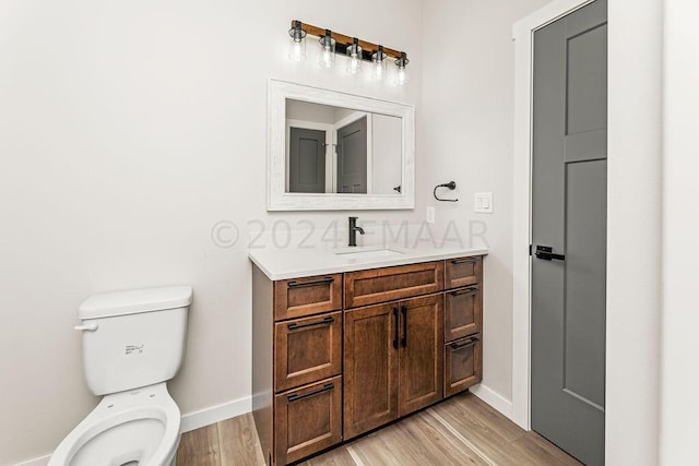 bathroom with wood-type flooring, toilet, and vanity