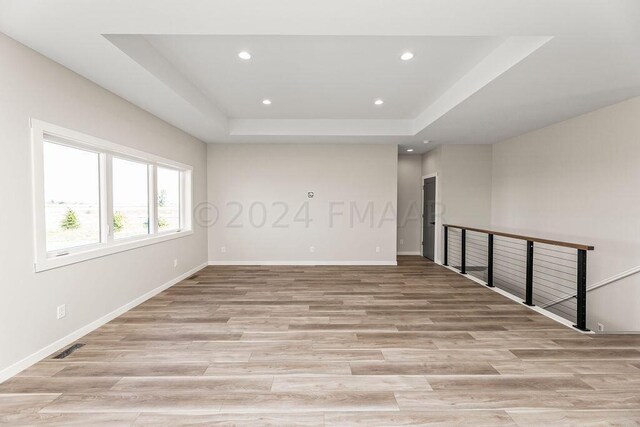 spare room featuring light hardwood / wood-style floors and a tray ceiling