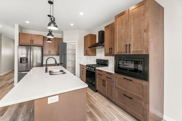 kitchen with black appliances, sink, backsplash, an island with sink, and wall chimney exhaust hood