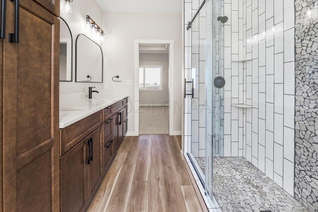 bathroom with a shower with shower door, hardwood / wood-style flooring, and double sink vanity