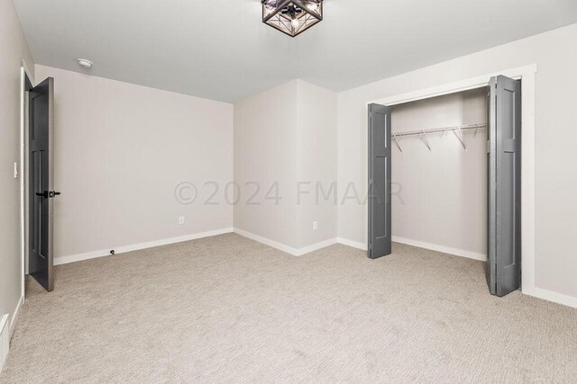 unfurnished bedroom with light carpet and a closet