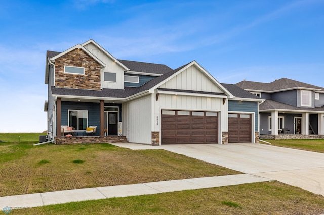 view of front of house with board and batten siding, a front yard, stone siding, and an attached garage