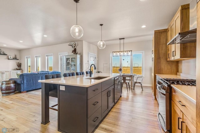 kitchen featuring appliances with stainless steel finishes, light countertops, wall chimney range hood, and a sink