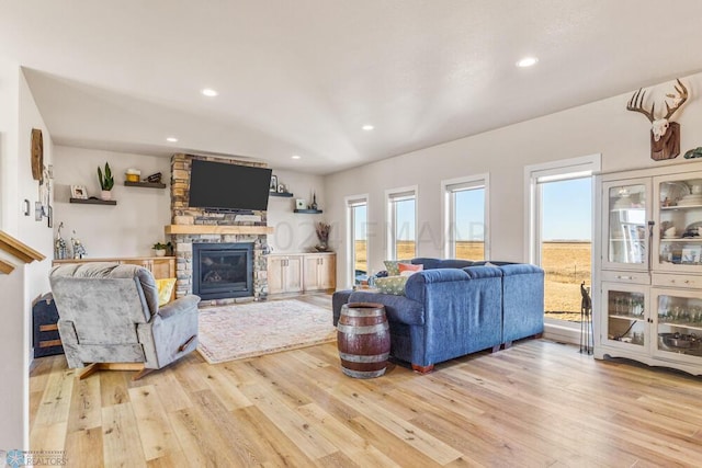 living room with a stone fireplace, recessed lighting, and light wood-style floors
