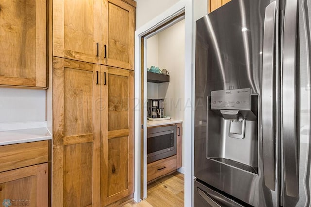 kitchen with light countertops, brown cabinetry, light wood-type flooring, and stainless steel appliances