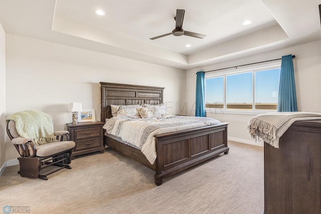bedroom with a tray ceiling, baseboards, and light colored carpet