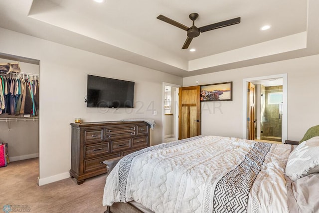 bedroom featuring a spacious closet, carpet flooring, baseboards, and a tray ceiling