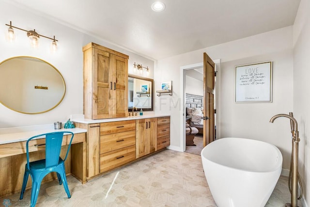 ensuite bathroom featuring vanity, ensuite bathroom, baseboards, and a freestanding tub