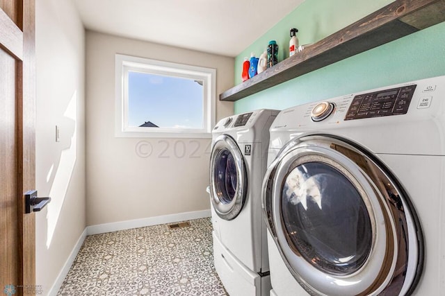 washroom with baseboards, light floors, laundry area, and washer and clothes dryer