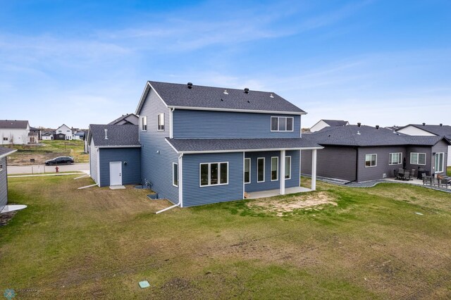 back of house with a patio, a yard, a residential view, and roof with shingles