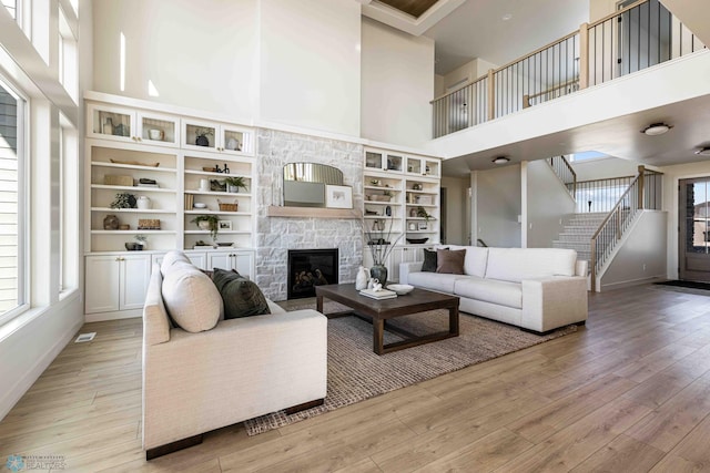 living room with light wood-style floors, a healthy amount of sunlight, a towering ceiling, and stairs