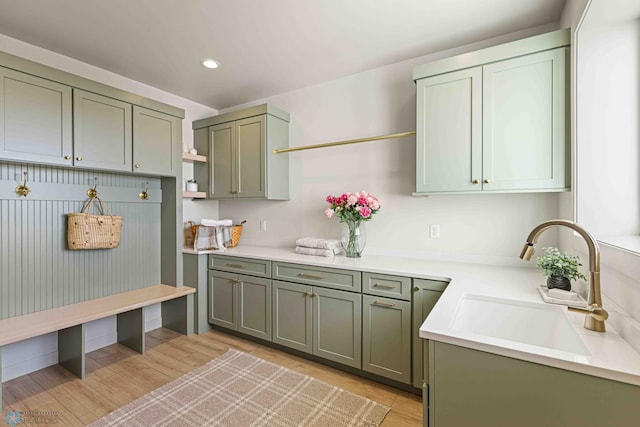 kitchen featuring open shelves, green cabinetry, a sink, light countertops, and recessed lighting