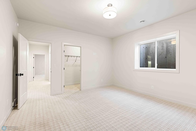 unfurnished bedroom with a closet, baseboards, a spacious closet, and carpet