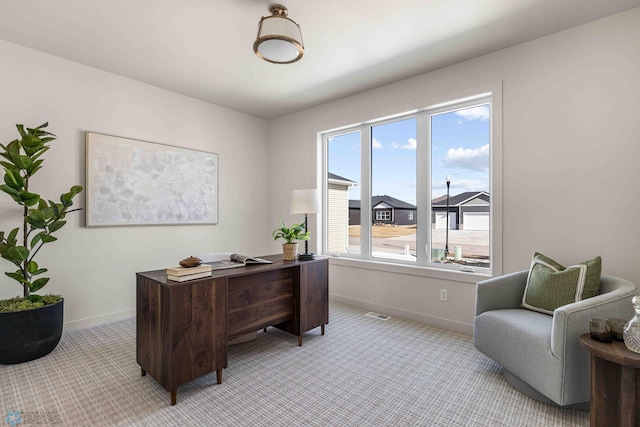 office space with baseboards, plenty of natural light, and light carpet