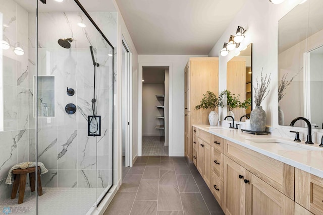 bathroom with a sink, a walk in closet, a marble finish shower, and double vanity