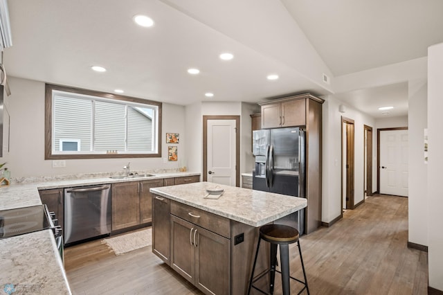 kitchen with a kitchen island, sink, light hardwood / wood-style floors, and stainless steel appliances