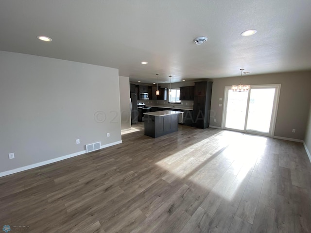 unfurnished living room featuring dark hardwood / wood-style flooring and an inviting chandelier