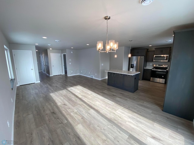 kitchen with hanging light fixtures, hardwood / wood-style flooring, a kitchen island, stainless steel appliances, and a chandelier