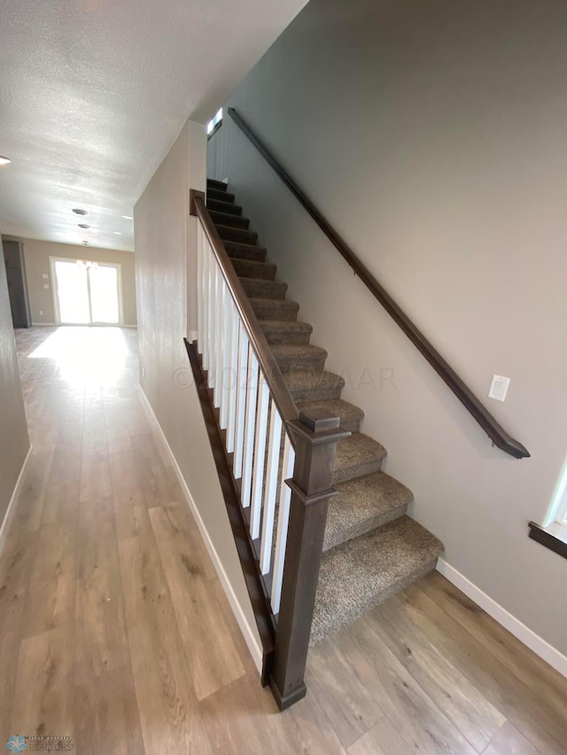 staircase featuring wood-type flooring and a textured ceiling