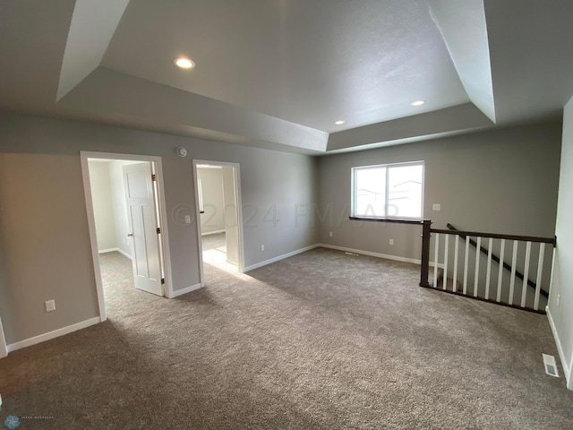 unfurnished room featuring a raised ceiling and carpet floors