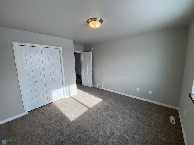 unfurnished bedroom featuring dark colored carpet and a closet