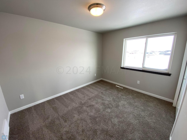 unfurnished room featuring dark carpet