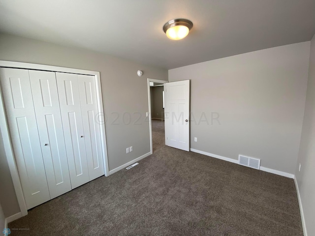 unfurnished bedroom featuring a closet and dark carpet