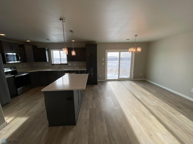 1316 Southview Dr SW, Glyndon, MN 56547 - kitchen featuring appliances with stainless steel finishes, a chandelier, light countertops, a center island, and light wood-type flooring