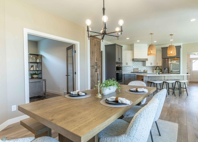 dining room with an inviting chandelier, light hardwood / wood-style floors, and sink