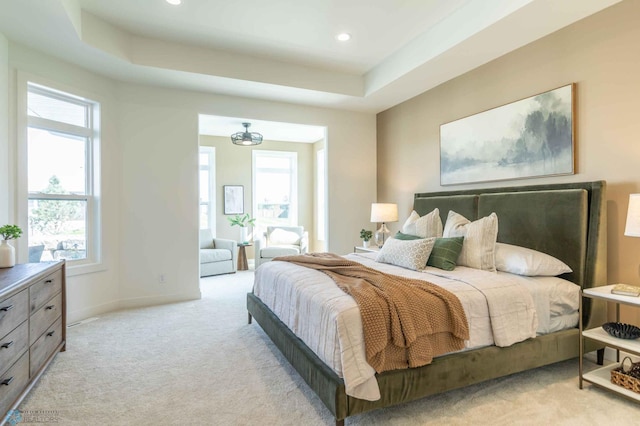 bedroom with a tray ceiling and light colored carpet