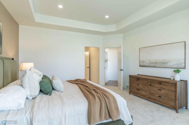 bedroom with a raised ceiling and light carpet