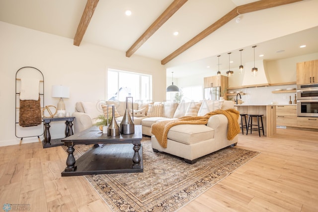 living room with sink, light hardwood / wood-style flooring, and lofted ceiling with beams