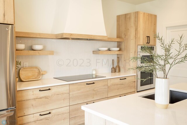 kitchen with light brown cabinetry, stainless steel appliances, and premium range hood