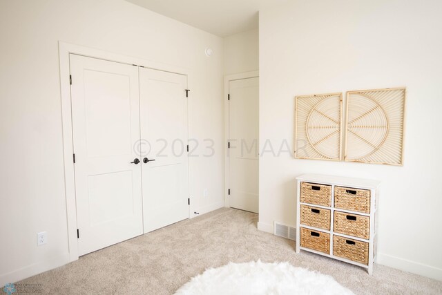 unfurnished bedroom with light carpet and a closet