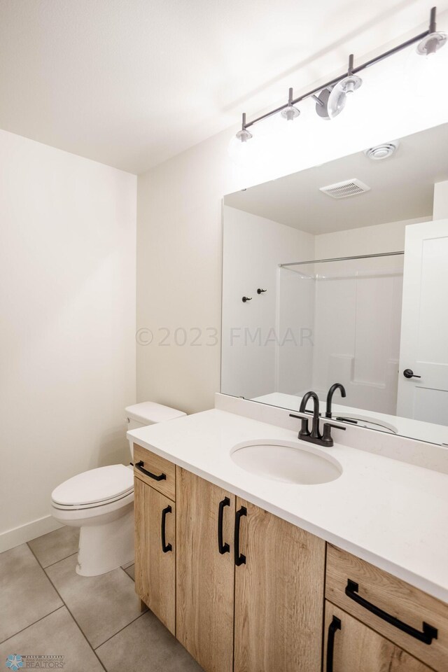 bathroom with vanity, tile patterned floors, toilet, and walk in shower