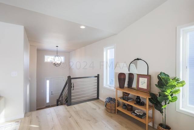 foyer entrance with light hardwood / wood-style flooring, a wealth of natural light, and a notable chandelier